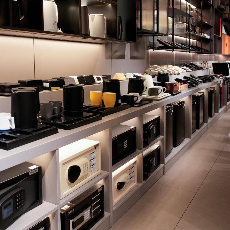 A detailed exhibition of hotel guest room electrical appliances, including modern coffee machines, electric kettles, hair dryers, and in-room safes.JPG