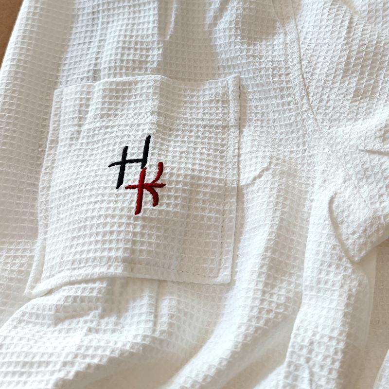 White waffle weave hotel bathrobe pocket displaying custom dual-color black and red HK logo embroidery.jpg