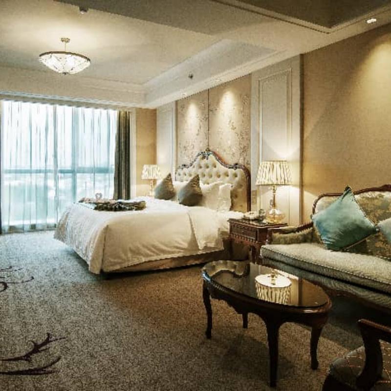 An ornate king-size bed with a carved wooden frame in a classic, European-inspired hotel room, demonstrating the enduring appeal of luxury materials and design.jpg