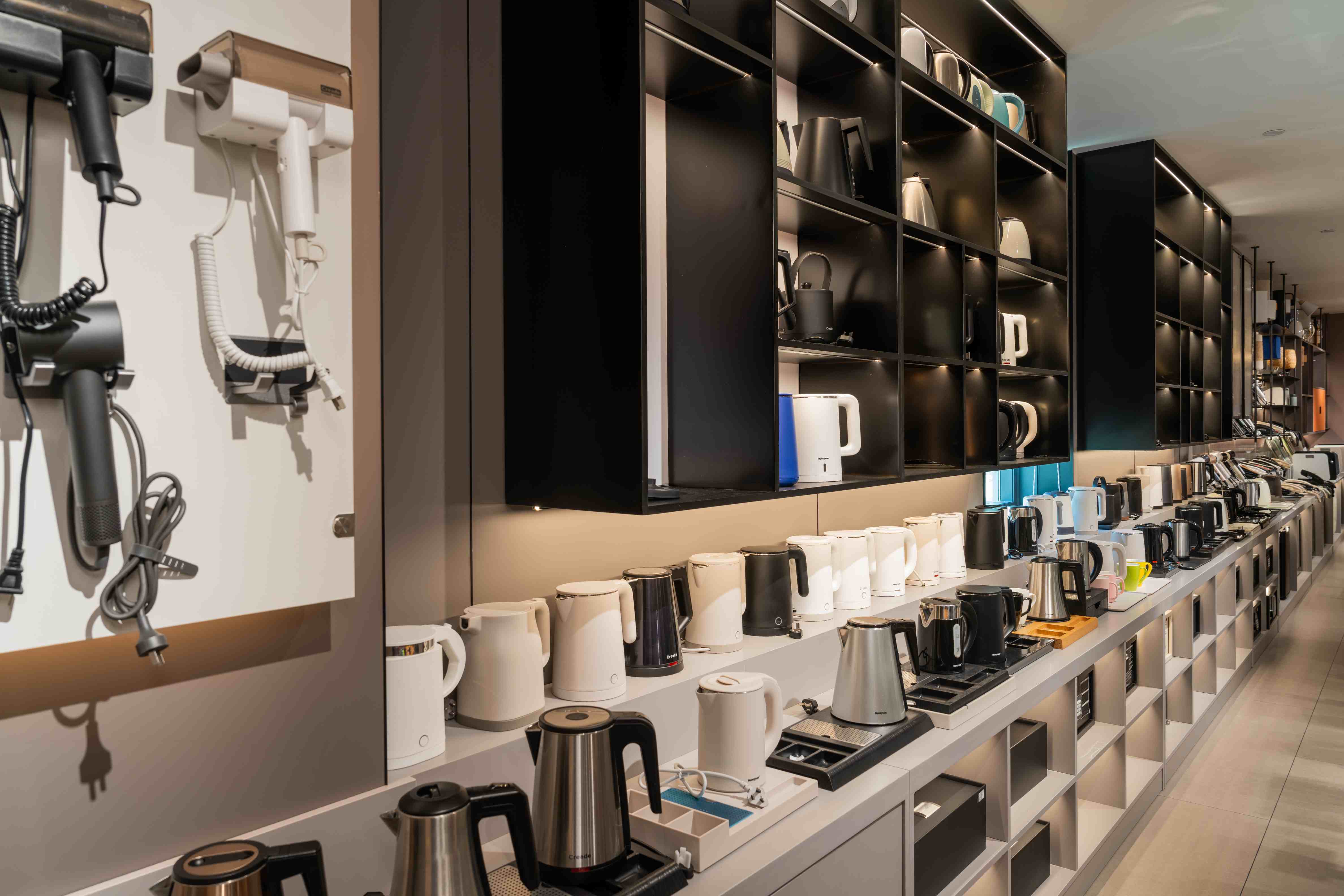 A neatly organized display of TAITANG hotel electric kettles and wall-mounted hair dryers, highlighting a wide variety of styles and ergonomic designs.