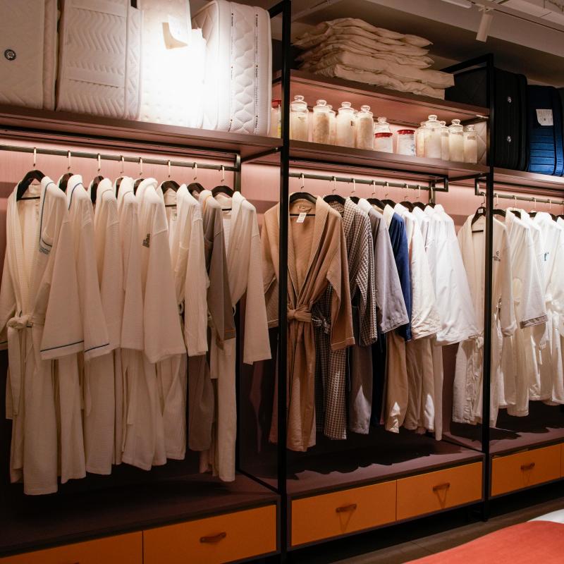 Plush white commercial hotel bathrobes on hangers inside Taitang hospitality supplies showroom for hotel procurement buyers.JPG