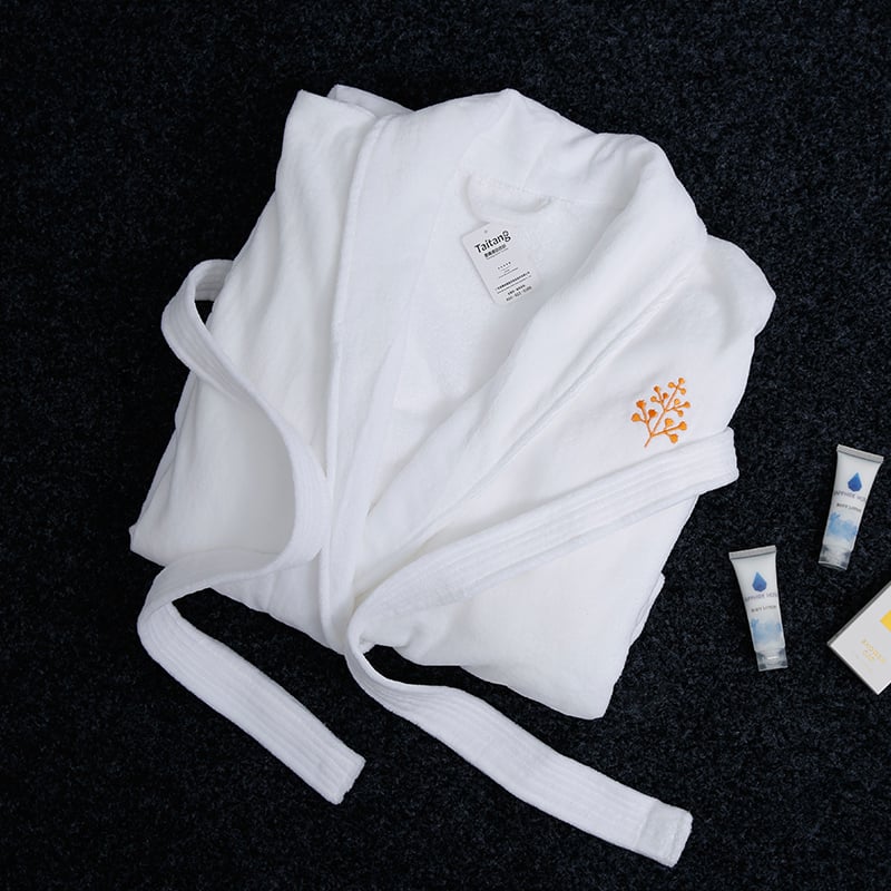 Neatly folded Taitang luxury hotel bathrobe with gold embroidery, displayed with premium hotel body lotions.jpg