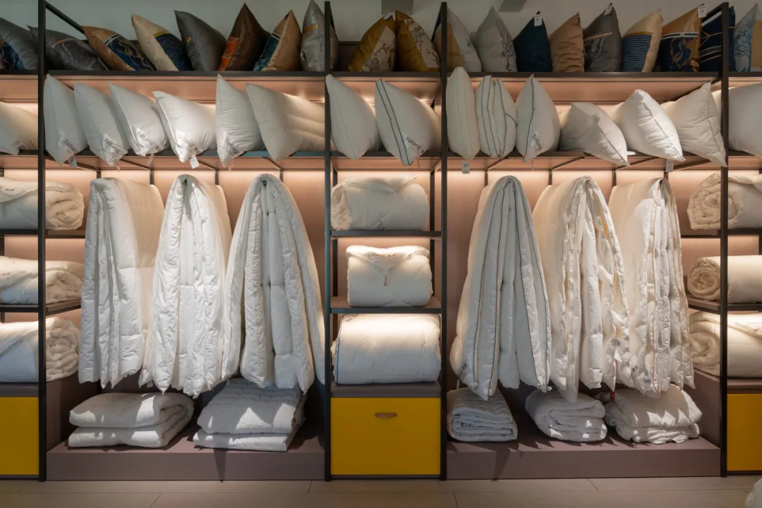 Showroom display of Taitang bulk hotel linens, featuring high-thread-count pillows, duvets, and comforters for luxury resorts.