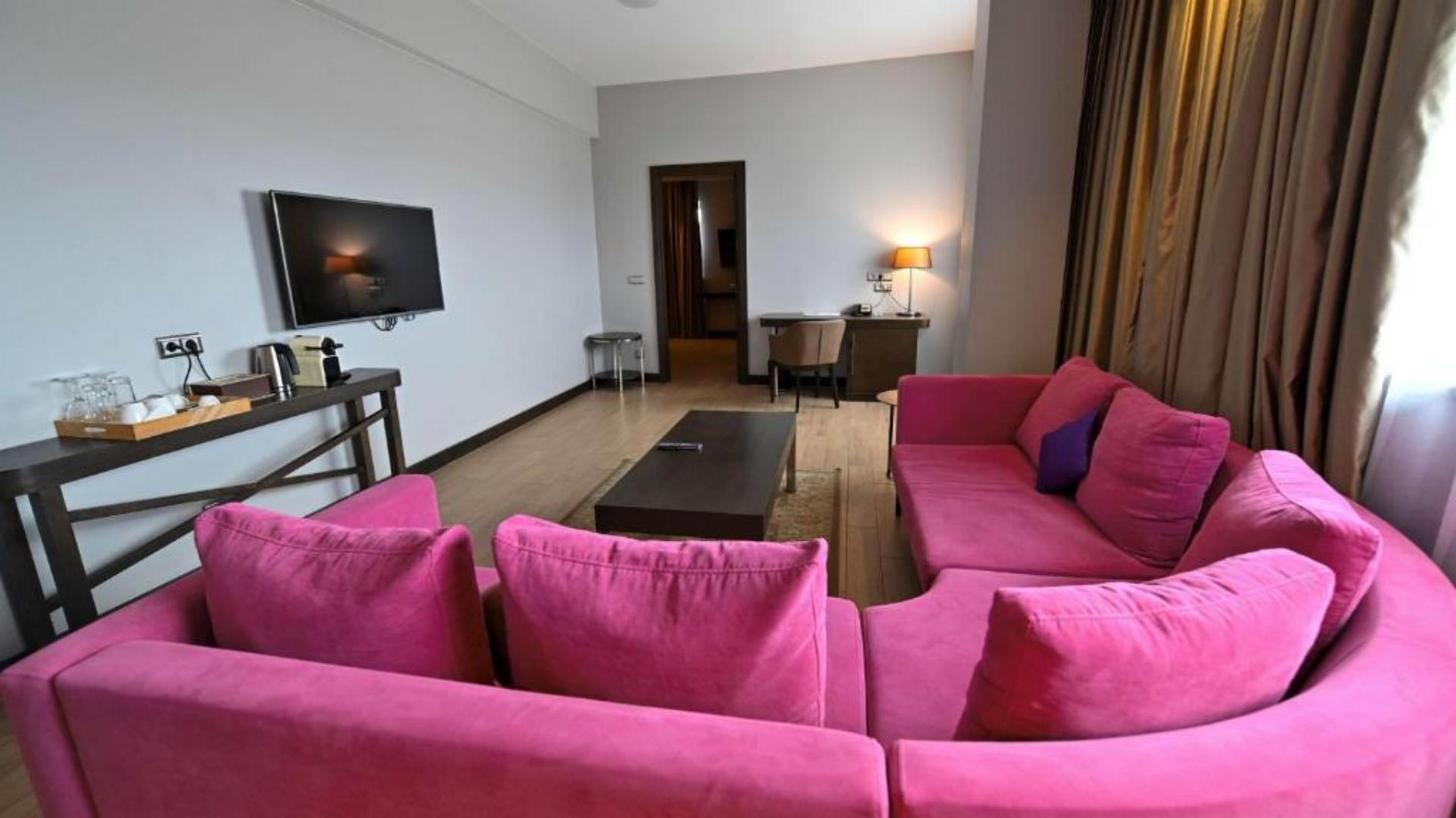 Luxury hotel executive suite living room featuring curved pink sofa and coffee table at Radisson Blu Hotel Abidjan Airport.jpg