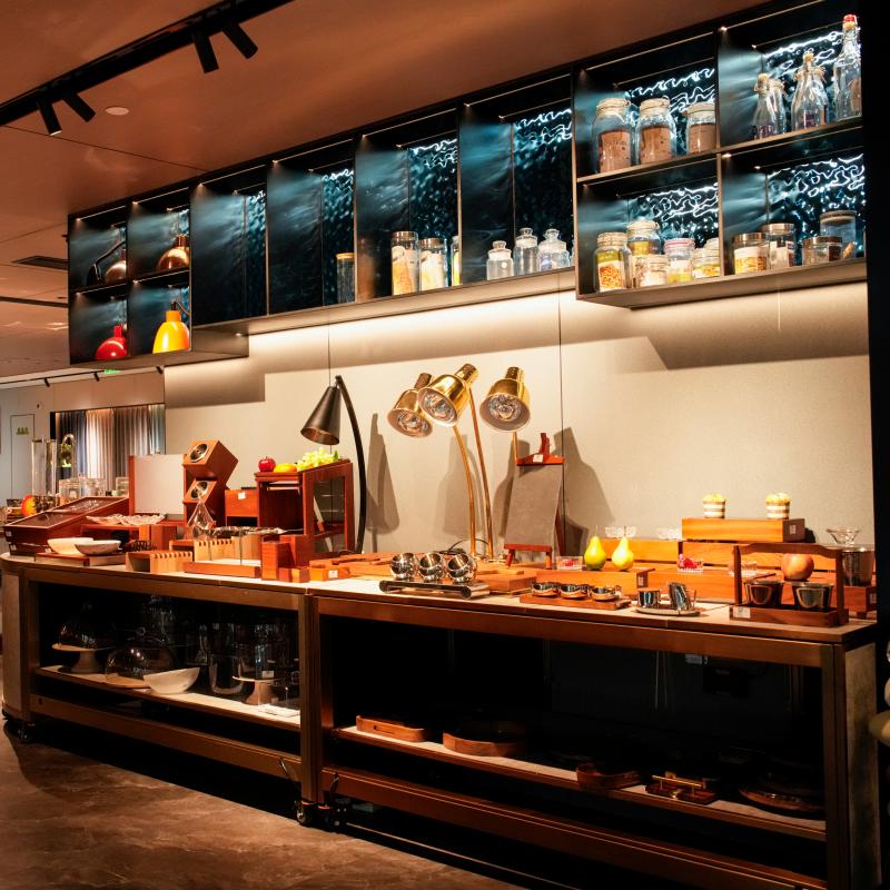 A long view down a well-organized commercial buffet line by Taitang Hospitality. It features extensive overhead warmth lights and a background with glass display cabinets.JPG