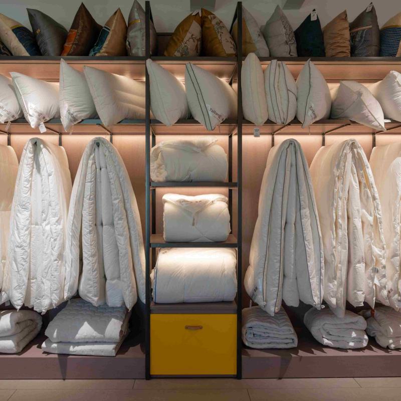 Organized showroom display rack filled with hotel bedding supplies, including pillows, duvets, and bathrobes.jpg