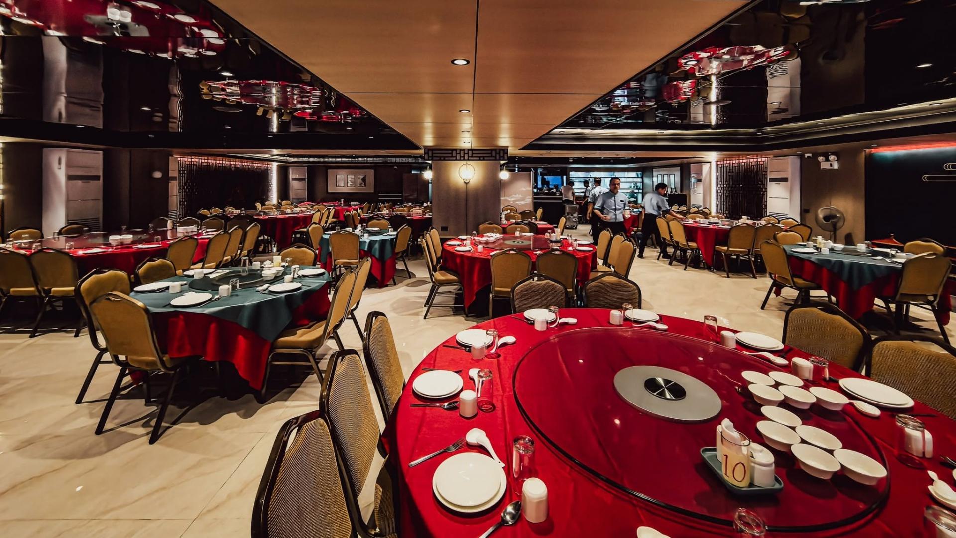 Spacious Chinese seafood restaurant banquet hall featuring large round dining tables with red tablecloths and lazy susans.jpg