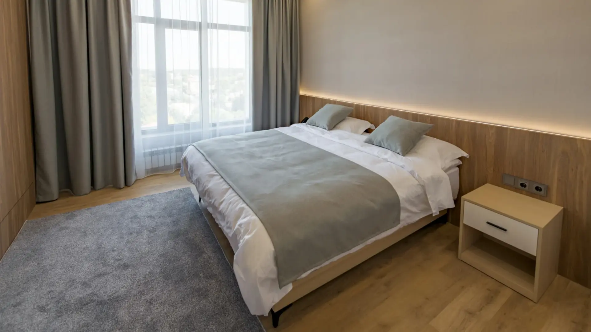Cozy hotel bedroom interior featuring a double bed made with crisp white cotton linens and decorative bed runner.webp