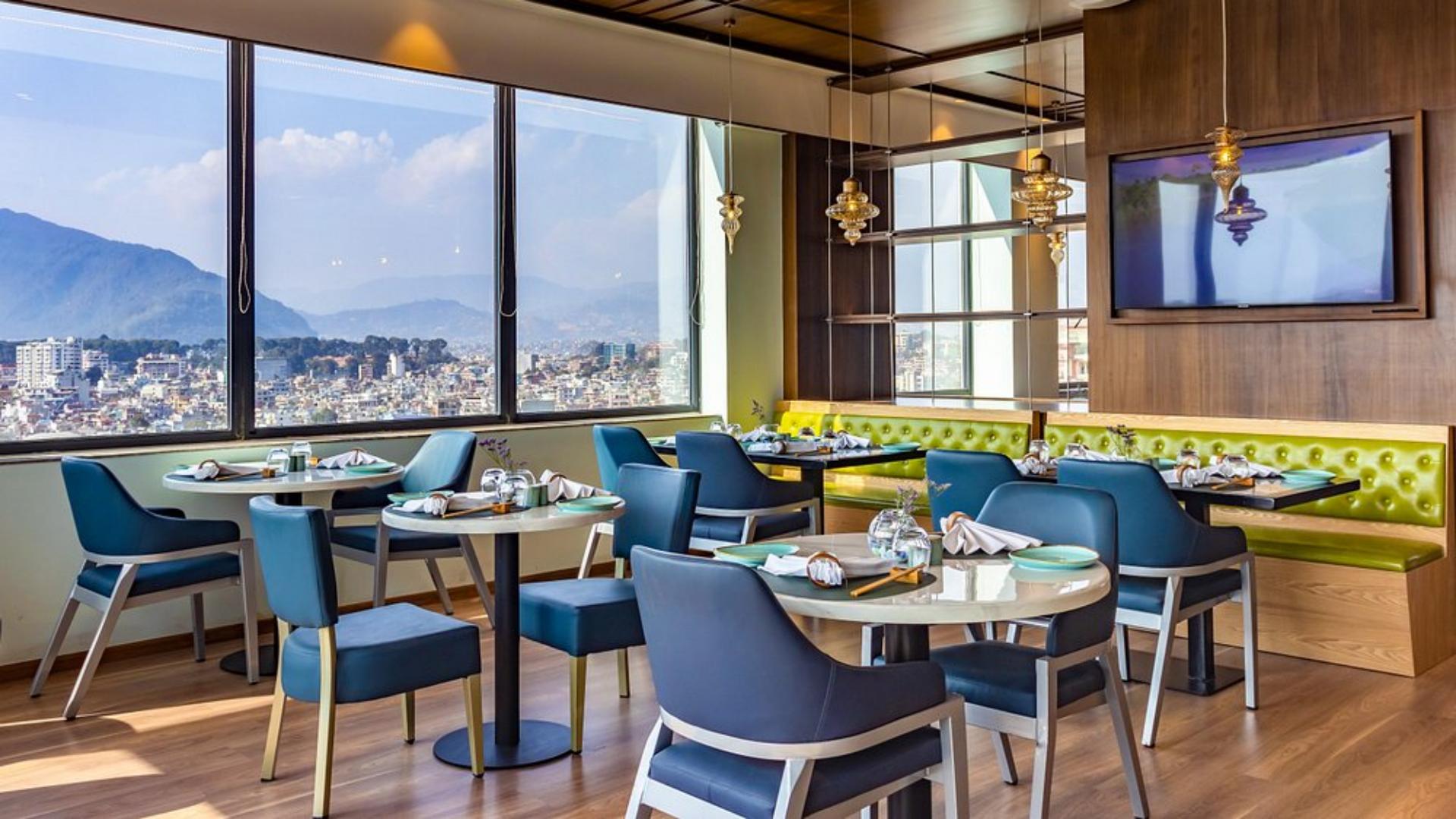 Hotel Asian fusion restaurant dining space with modern blue chairs, set dining tables, and large panoramic windows.jpg