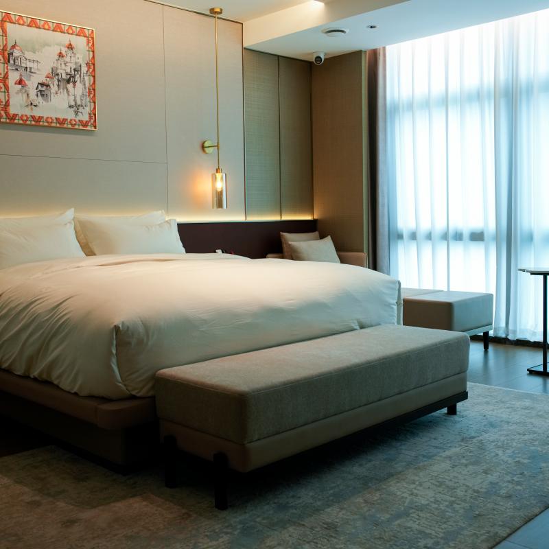 Modern hotel guestroom featuring a fully dressed king bed with Taitang high-loft duvet insert and premium sleeping pillows.JPG