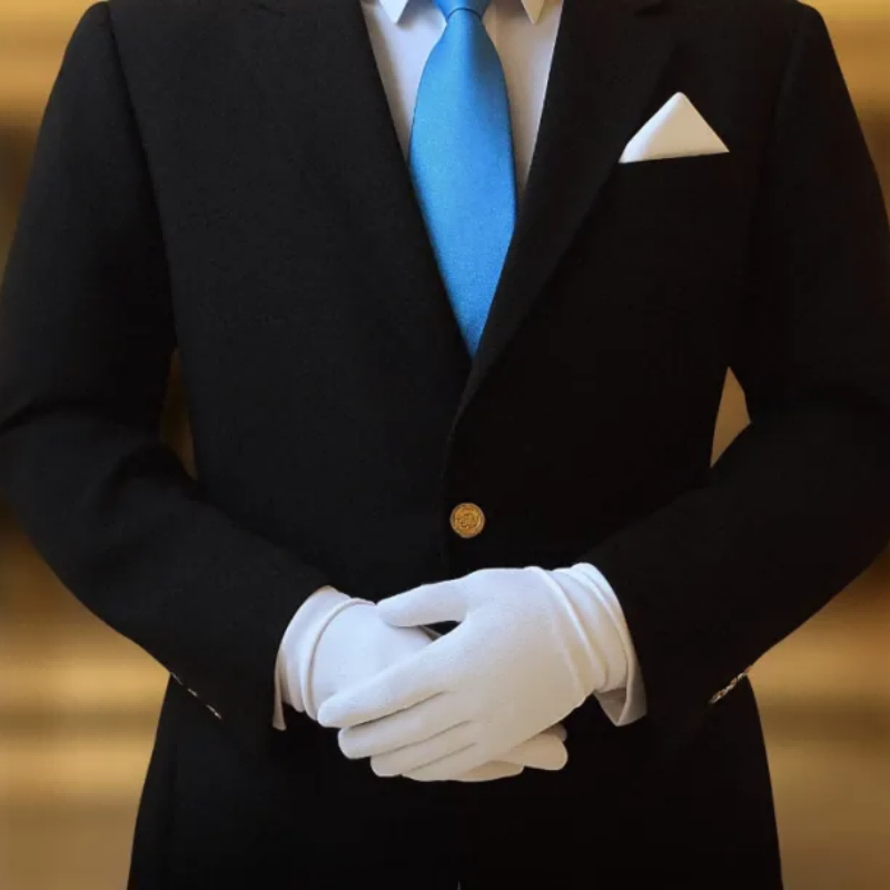 Close-up of a hotel butler in a dark suit, bright blue tie, and white gloves, showcasing refined hospitality details.png