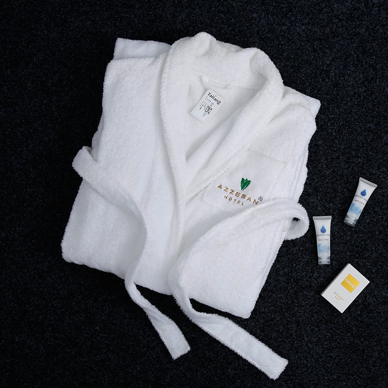 Folded Taitang luxury hotel bathrobe with custom hotel logo embroidery displayed on a dark background with guest room amenities.jpg