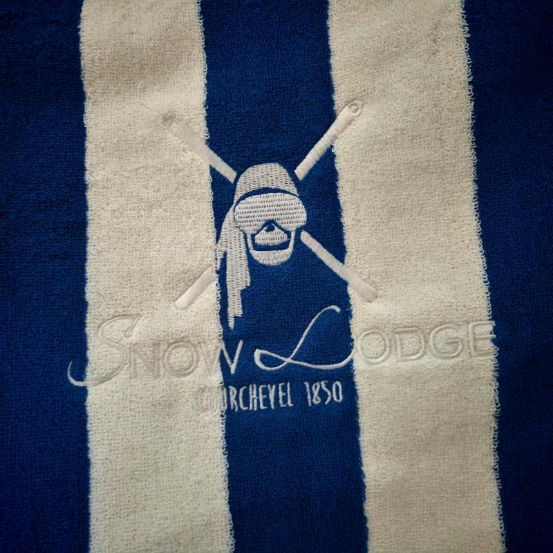 A detailed close-up shot of white embroidery on a blue and white striped terry towel.jpg