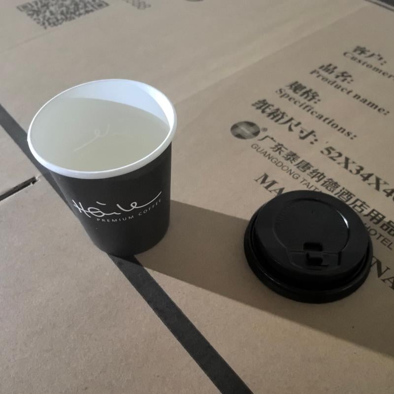 Custom matte black paper coffee cup with white printed Haile logo and matching lid displayed on Taitang export packaging.jpg