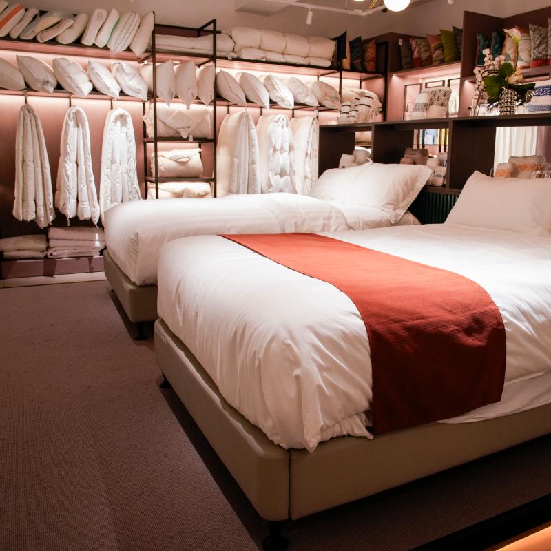 Close-up view of a complete hotel bedroom setup with white cotton linens, decorative red bed runner, and plush pillows in Taitang’s one-stop showroom.JPG