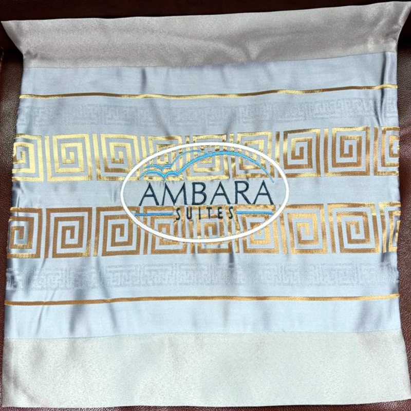 Custom embroidered hotel cushion cover with gold jacquard trim and Ambara Suites branding.png
