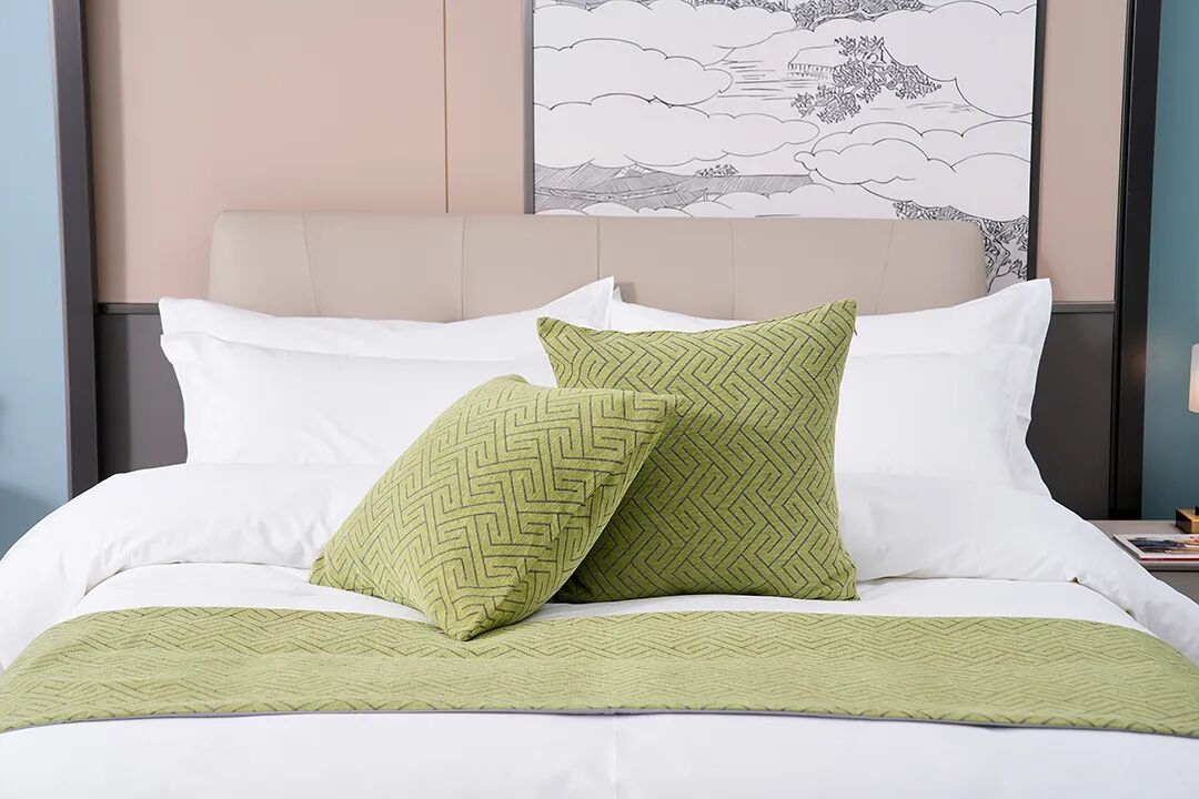 A fully made hotel bed with high-thread-count white linens and a green geometric pattern bed runner, showcasing TAITANG’s