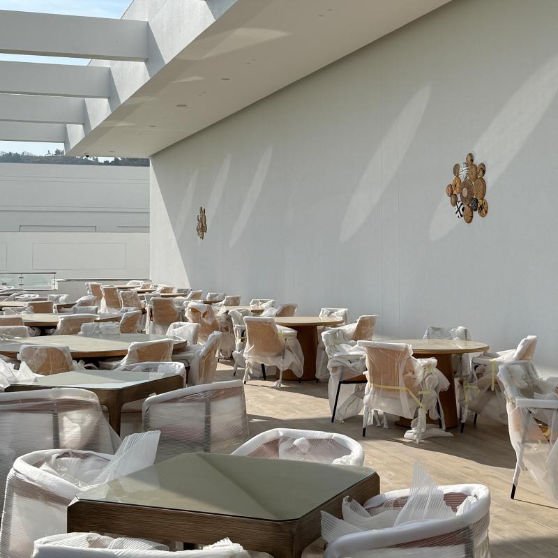 Spacious resort banquet hall arranged with round dining tables and protective-wrapped commercial dining chairs.jpg