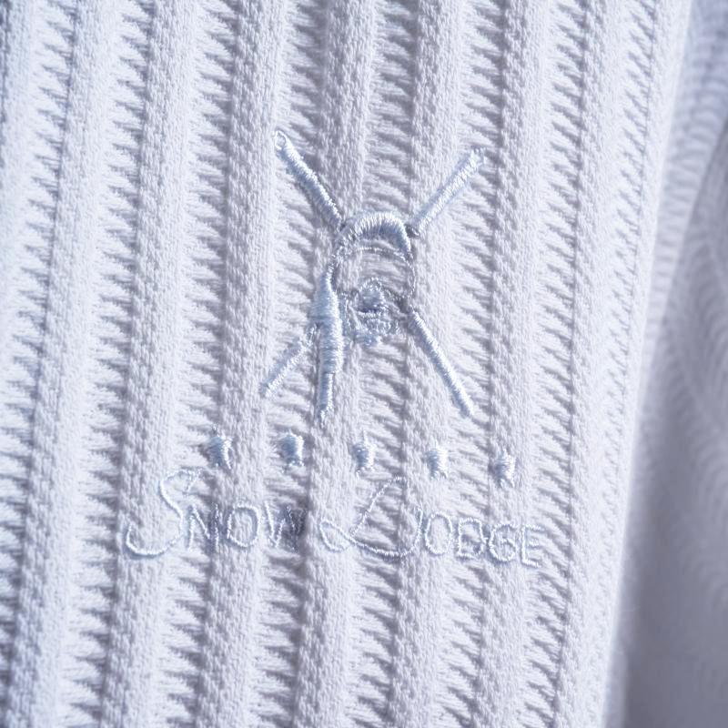 White textured hotel bathrobe featuring detailed custom embroidery of the Snow Lodge logo.jpg
