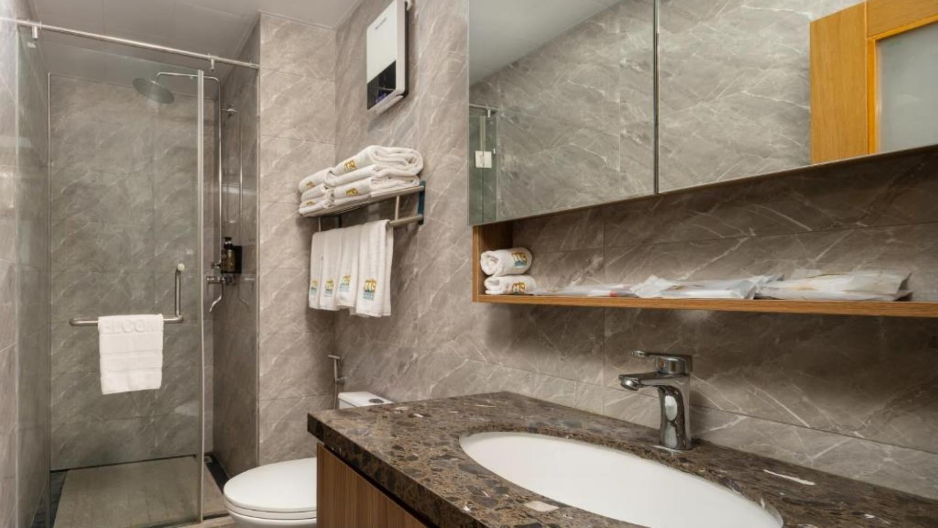 Modern hotel bathroom vanity and shower set up with clean folded white bath towels.jpg