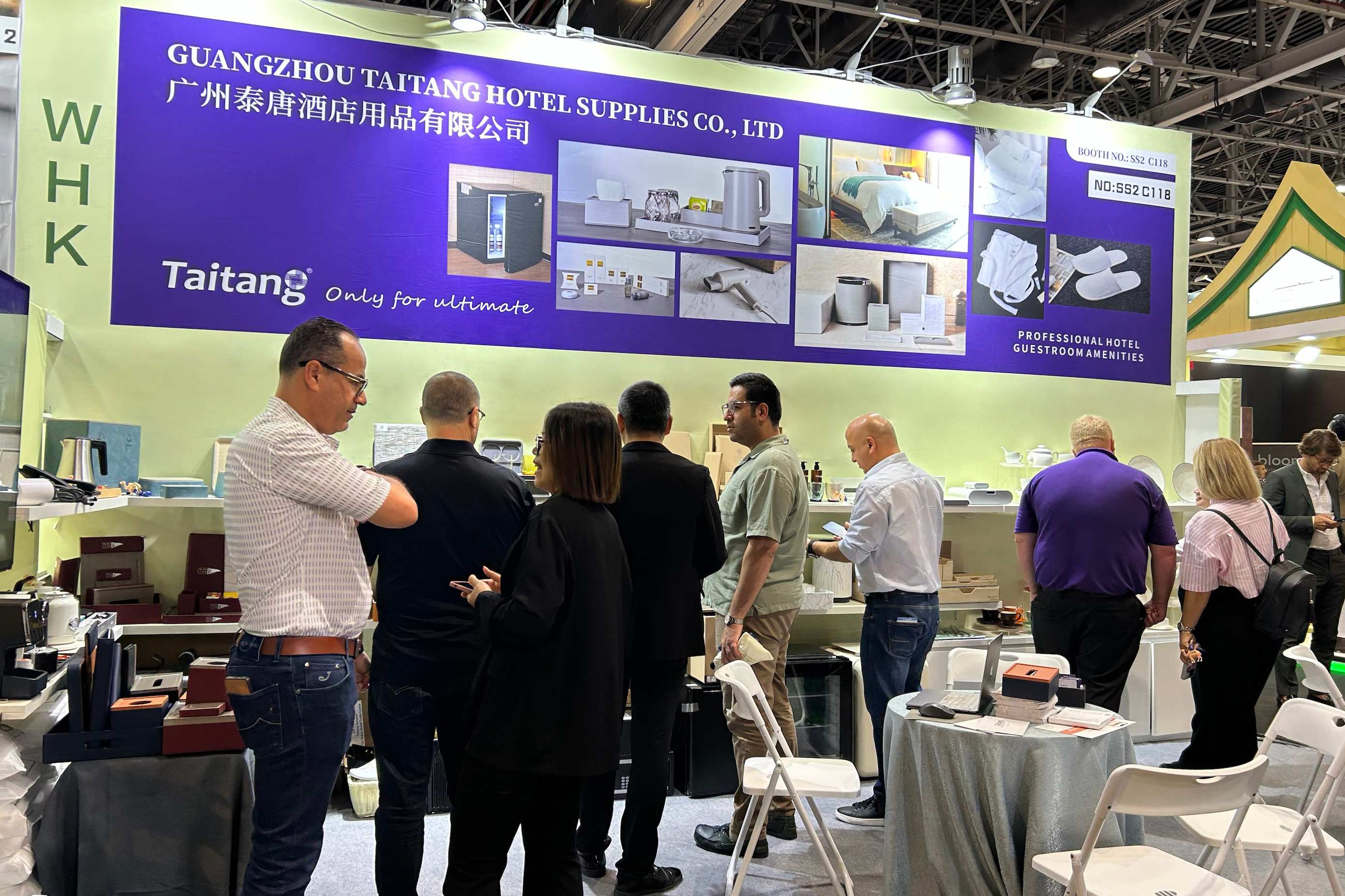 A busy scene at the TAITANG exhibition booth where international hotel procurement managers are discussing one-stop supply solutions with staff.
