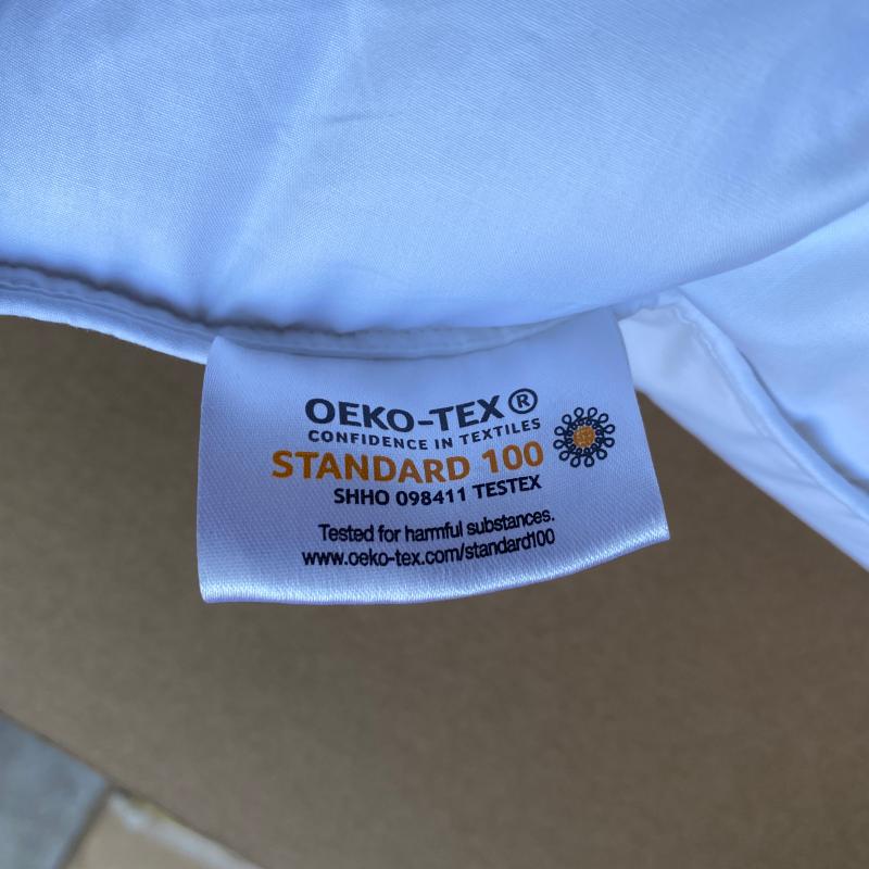 Close-up of OEKO-TEX STANDARD 100 fabric safety tag on white commercial hotel bedding.JPG