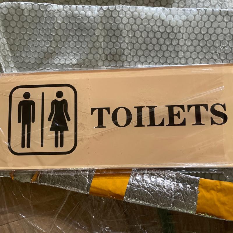 Clear acrylic restaurant TOILETS directional sign with male and female symbols undergoing pre-shipment quality check.JPG