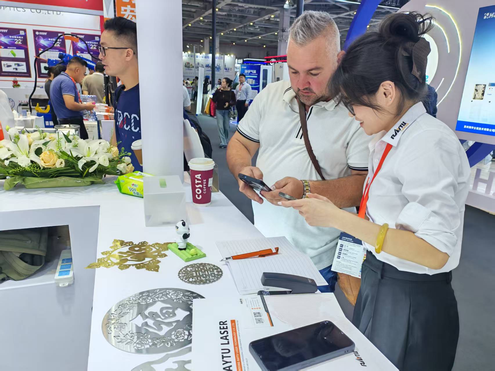 Visitor and Raytu team member standing beside a laser cutting machine at CIIF 2026.jpg