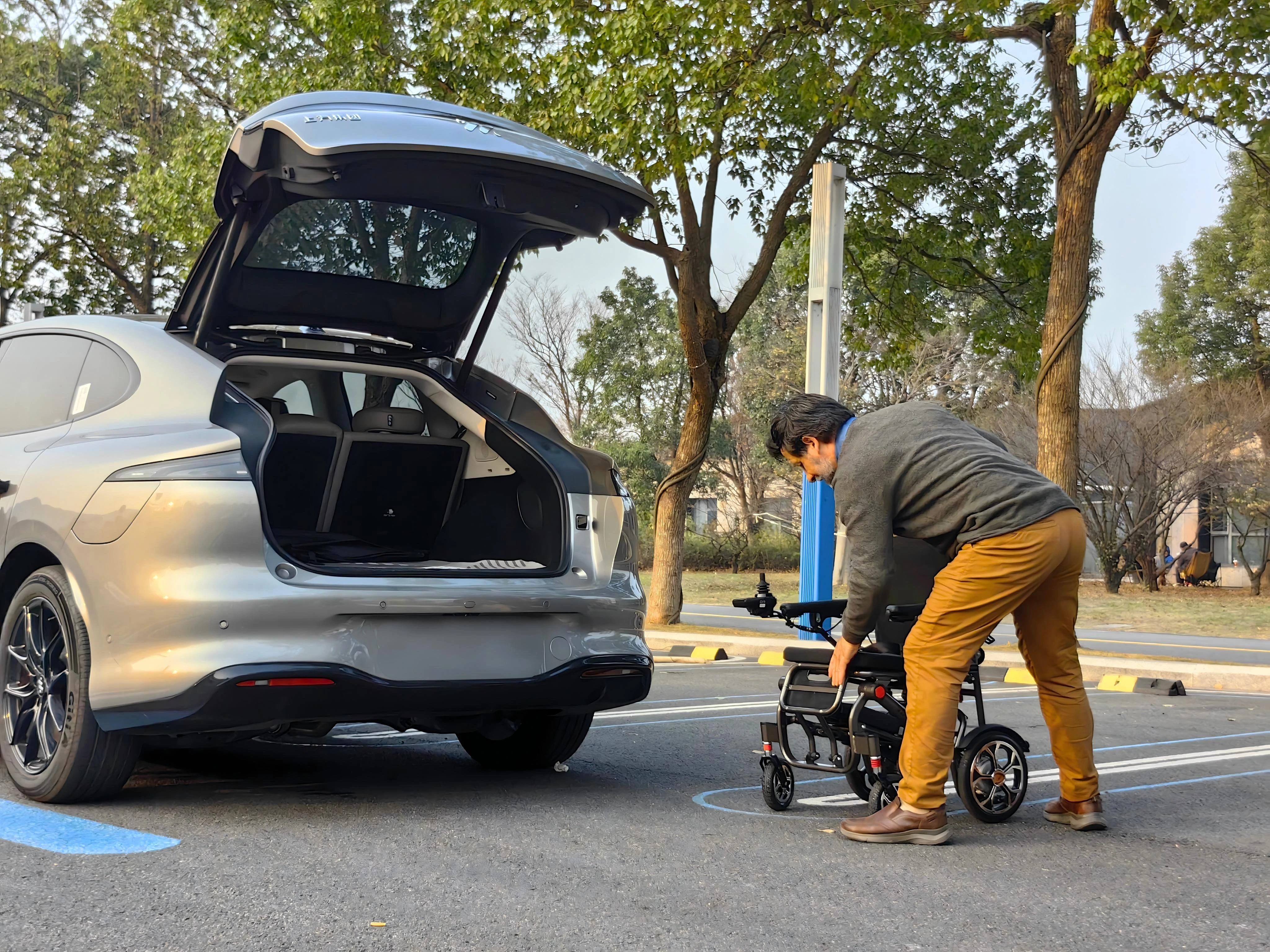 Dealer demonstrating electric wheelchair folding and loading