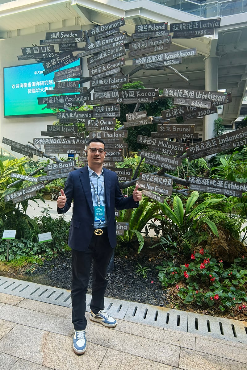 Dawson (Xiamen University EMBA participant) posing at BGI Group global partnership installation with country names.jpg