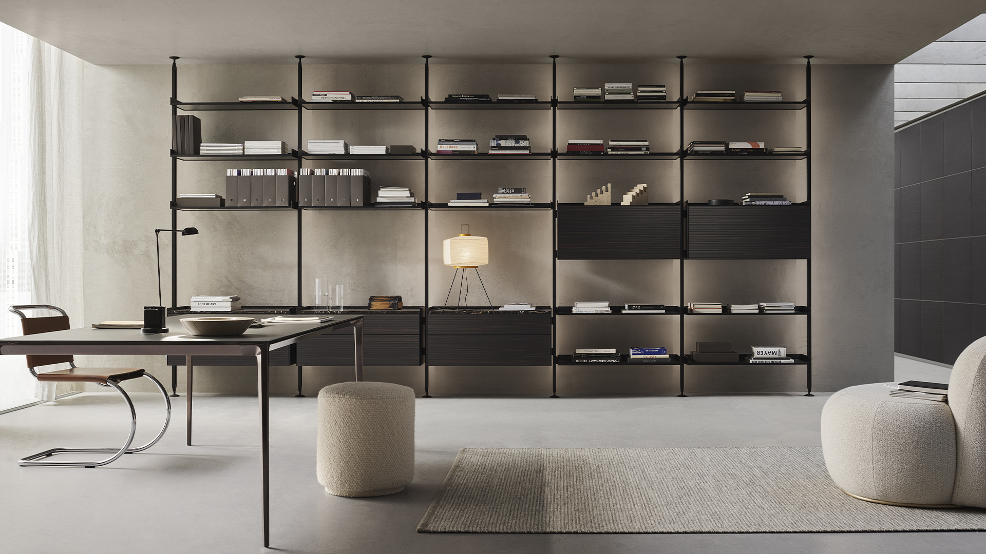 Black floor-to-ceiling modular bookshelf in a minimalist office and living space