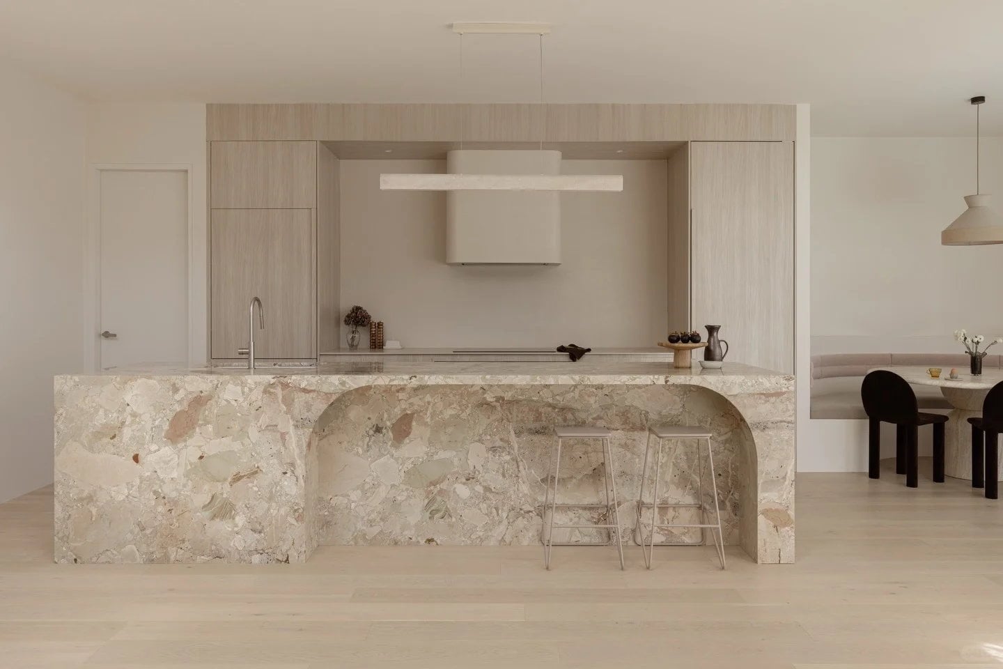 Custom kitchen island fabricated from pale Monet Garden Marble in a minimal light-toned interior.