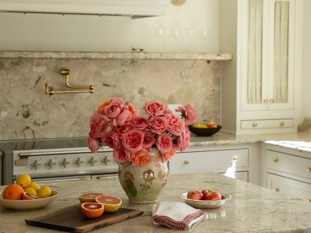 Monet Garden Marble kitchen countertops and backsplash in a light classic interior with flowers and brass fittings.