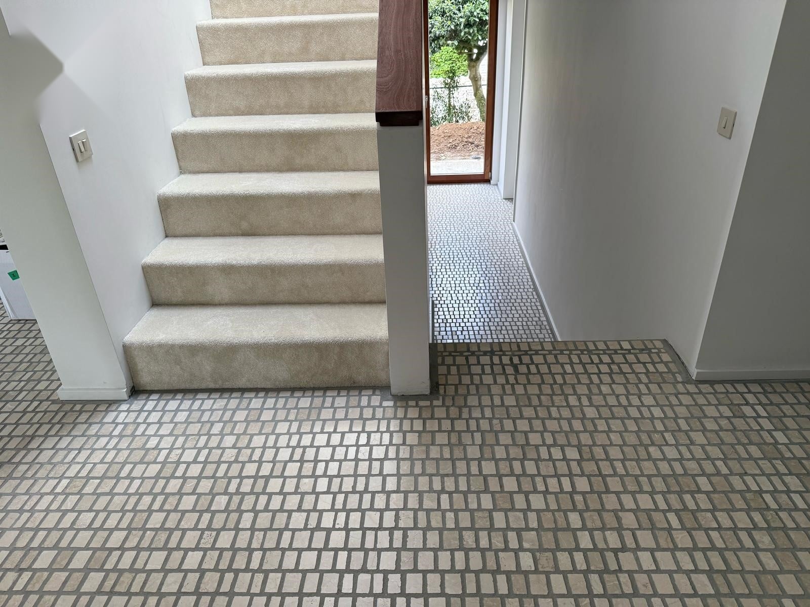 Rough-cut Botticino marble mosaic flooring at an interior entrance and staircase