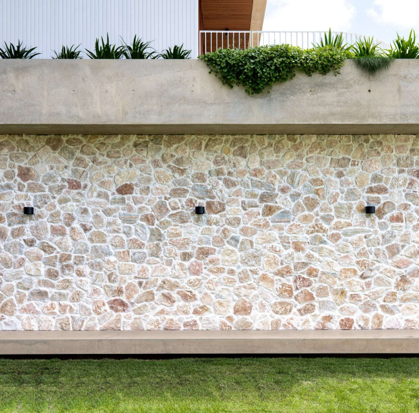 Warm loose stone cladding on a landscaped courtyard wall