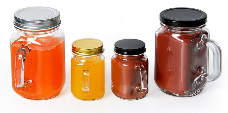 Two large and two small glass mason jars with handles are filled with drinks