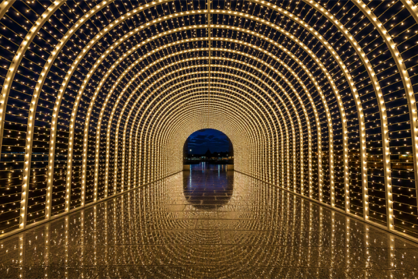 Illuminated 3D walk-through Christmas light tunnel made of warm-white light arches