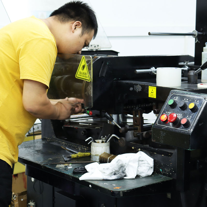 Worker operating printing press for custom sticker production