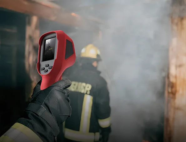 Firefighter holding the LSJ E310 Plus thermal imaging camera during a smoke-filled search and rescue operation