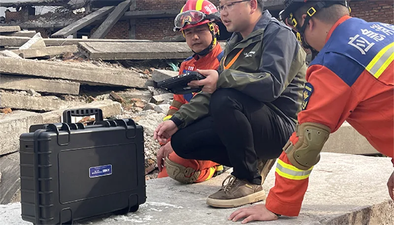 Rescue team operating a UWB radar life detector from a rugged case at a disaster site