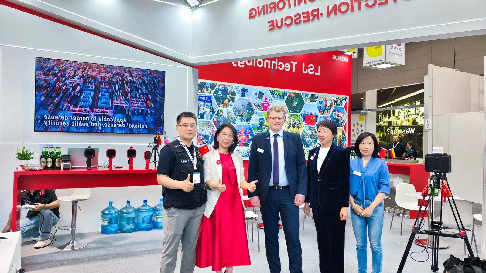 IMG-08 | LSJ Team Meeting International Partner LSJ representatives welcoming an international industry partner inside the company booth, with handheld thermal imaging devices displayed on the red counter