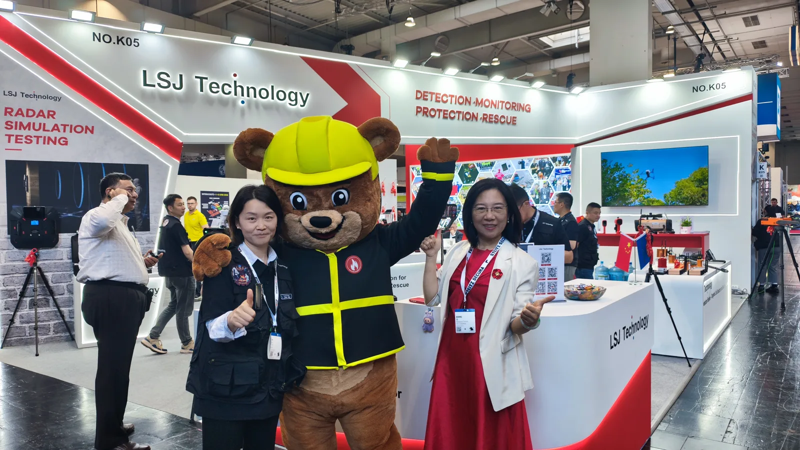 IMG-01 | LSJ Booth at Hannover Fire & Rescue 2026 LSJ Technology booth NO.K05 at the Hannover Fire and Rescue Exhibition 2026, with detection, monitoring, protection and rescue branding and a firefighter mascot welcoming visitors