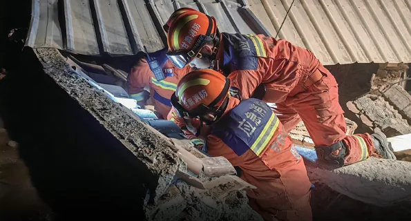 Rescue team using radar life detection through collapsed concrete at an earthquake building collapse site at night