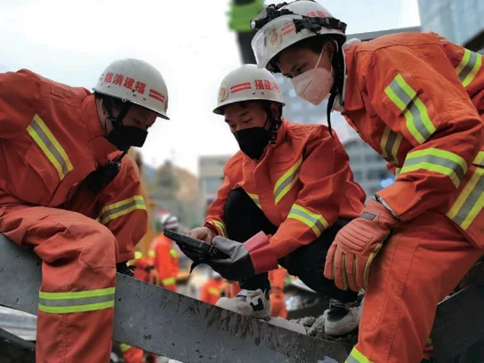Rescuers using handheld detection equipment on rubble at the Quanzhou hotel collapse site