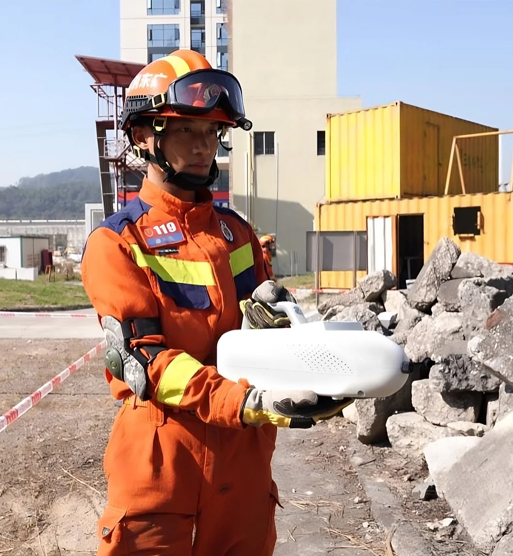 Fire rescue operator in protective gear holding the LSJ SEED-PM trace detector during a hazardous-materials inspection at a rubble search-and-rescue site