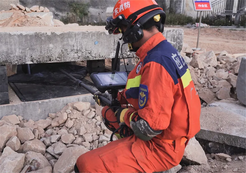 Rescuer operating a handheld search and rescue camera to locate survivors in rubble