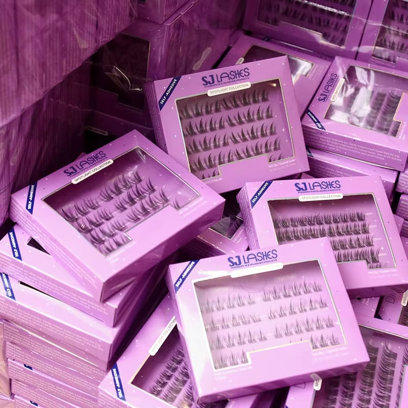 Stacked purple self-adhesive segmented lash boxes with large windows showing glue-free lash clusters in rows - custom private label lash packaging production