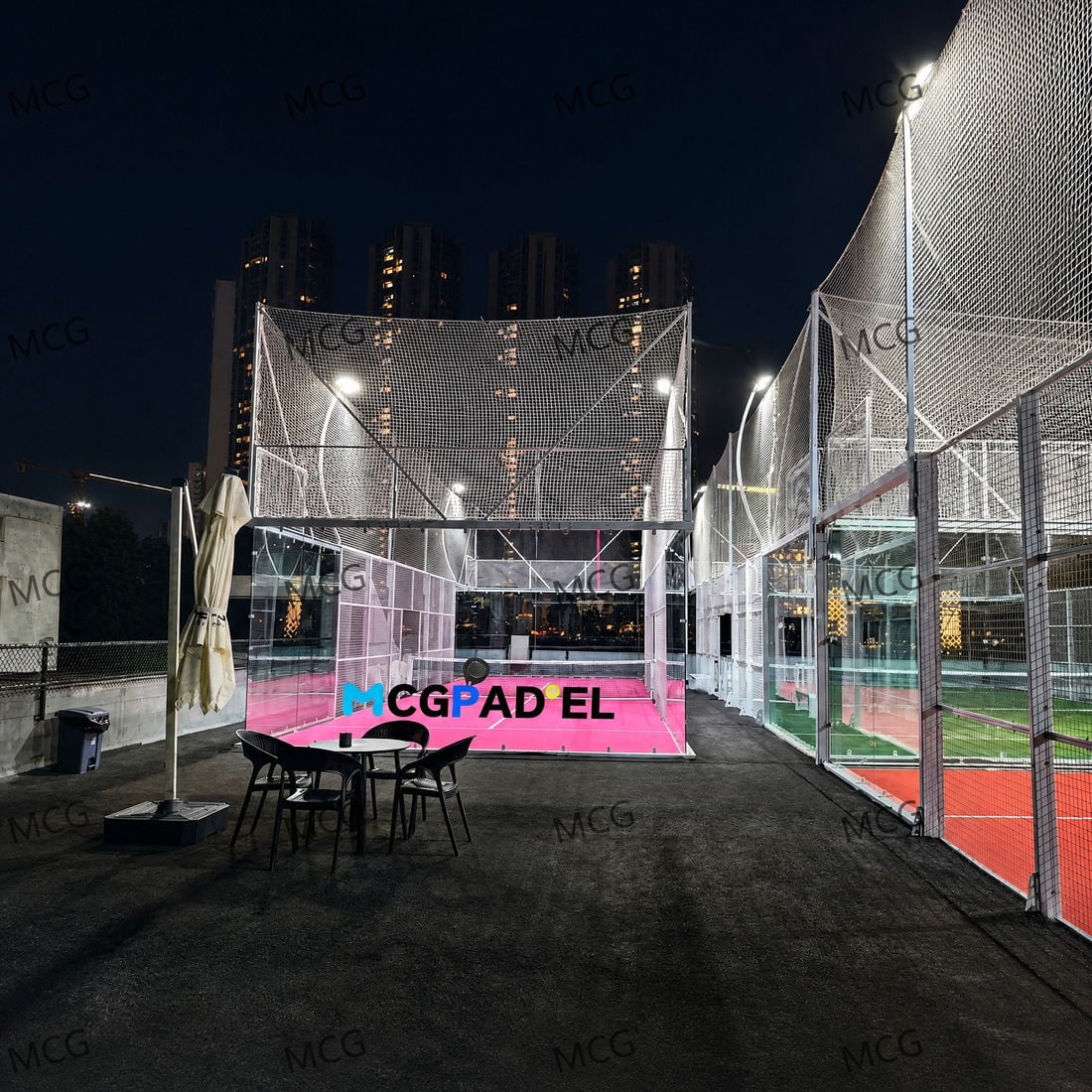 Outdoor padel club at night with three courts in pink, green and red turf under LED floodlights