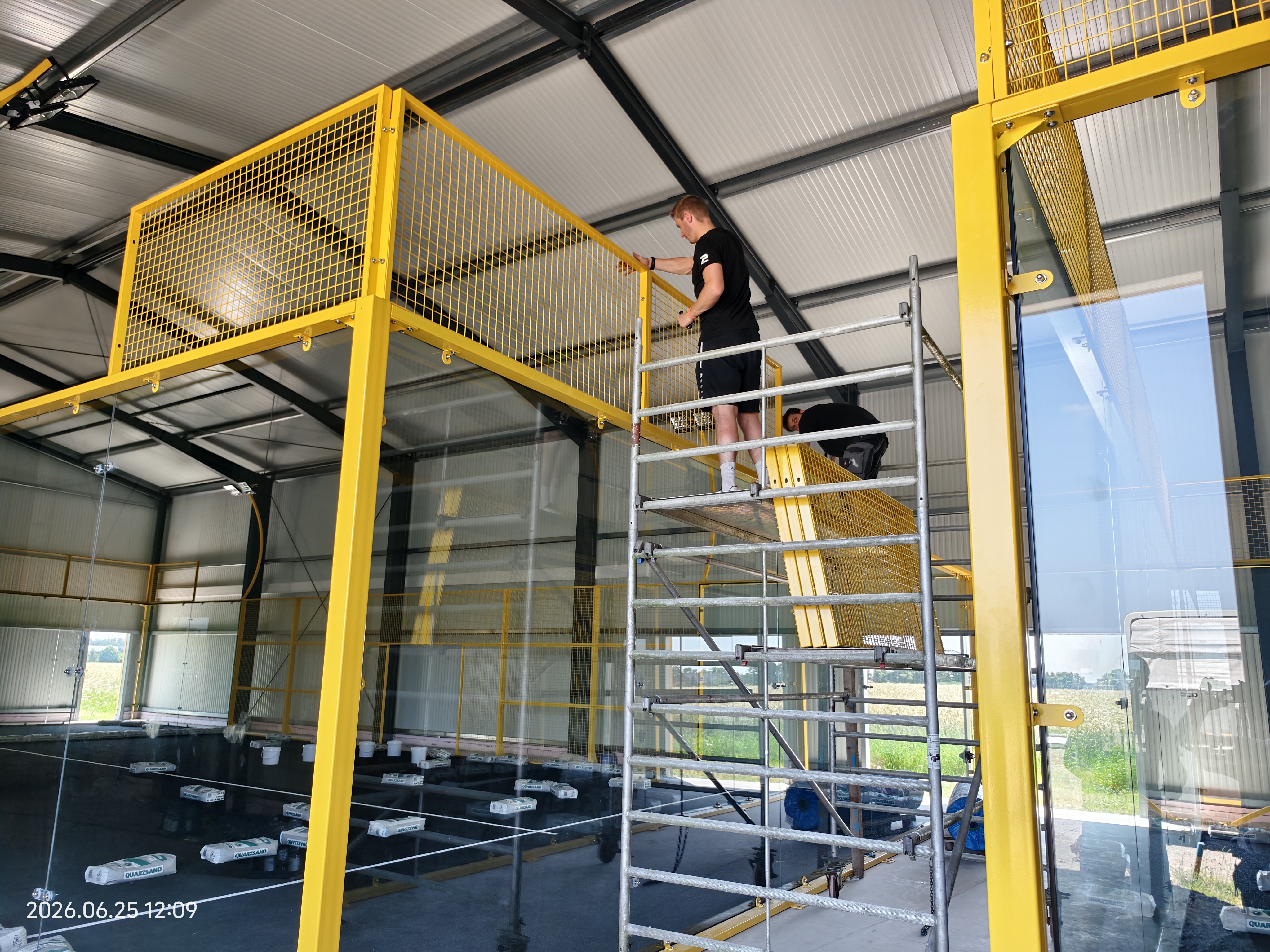 High altitude assembly of fence - workers install yellow mesh on scaffolding