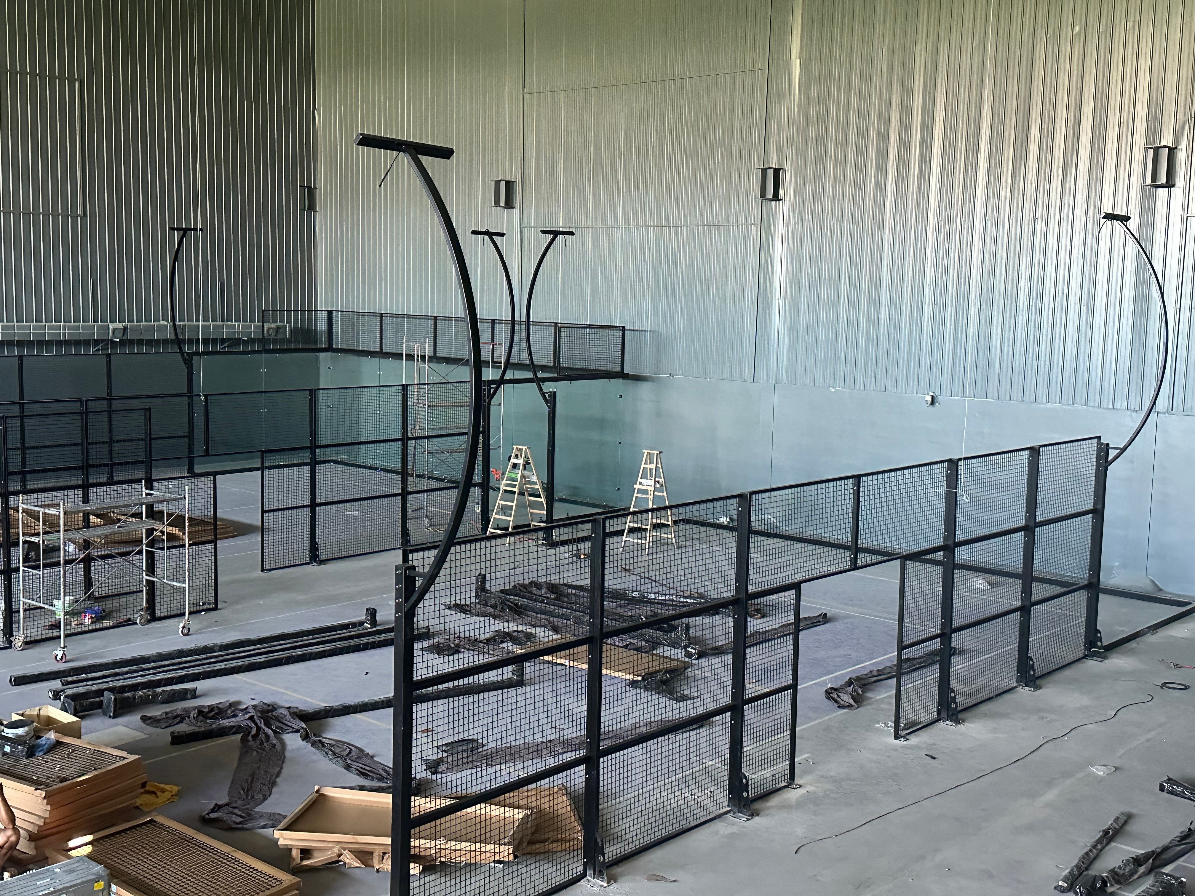 Construction of fence frame - installation of yellow columns and glass rear wall